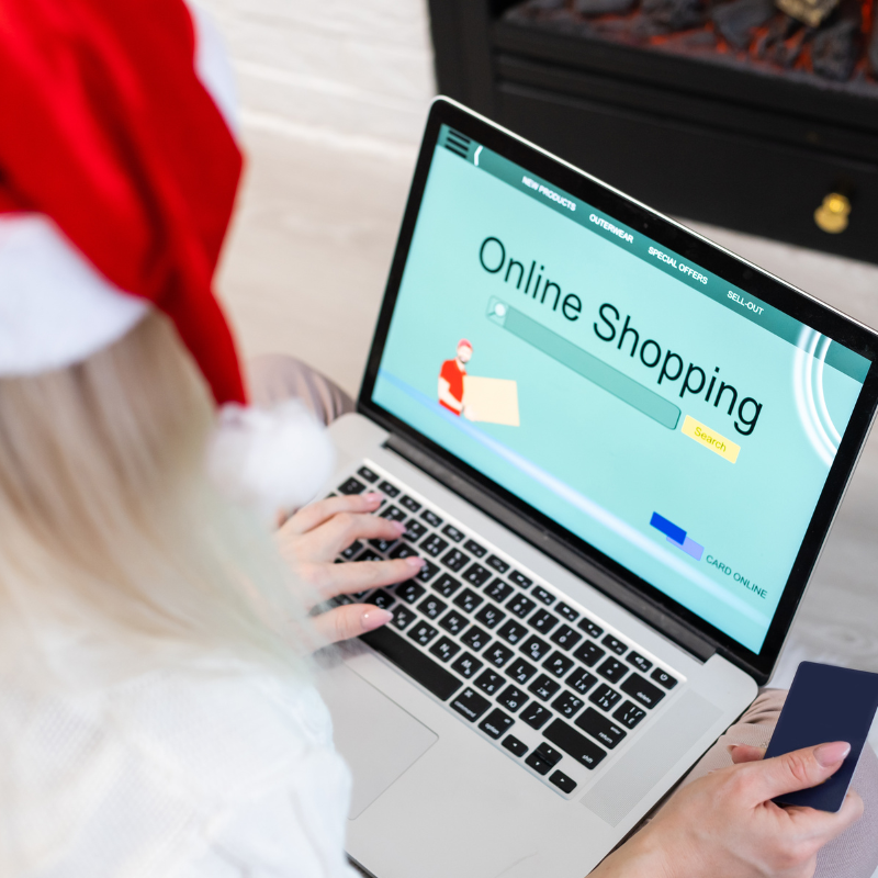 A lady in a Santa hat does online shopping for the holidays.