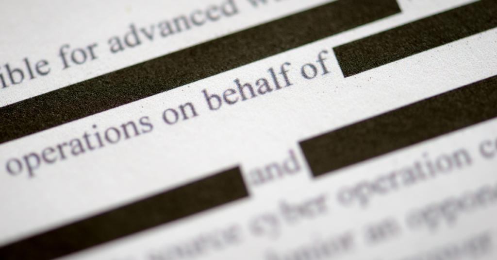 A close-up of a document with redacted black bars over copy.