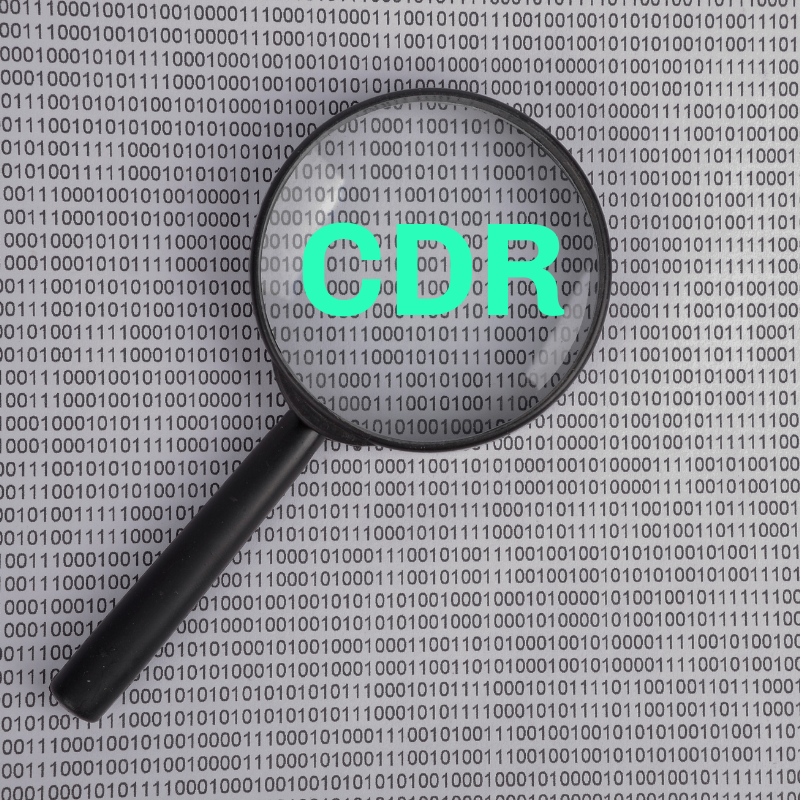 A magnifying glass with the acronym CDR inside of it on top of a paper with ones and zeros