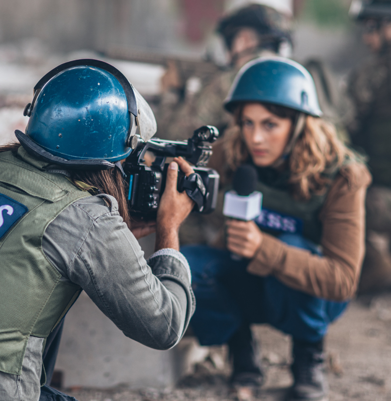 A camera person and a news reporter duck as they cover news inside of a battlefield