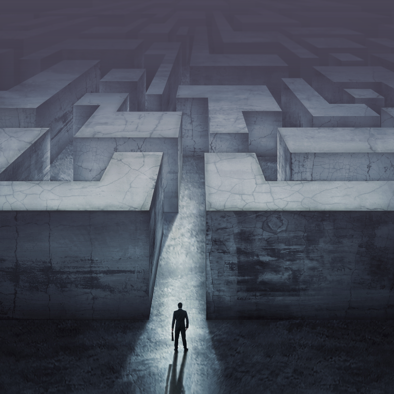 A man stands in front of the entrance to a large maze made out of concrete