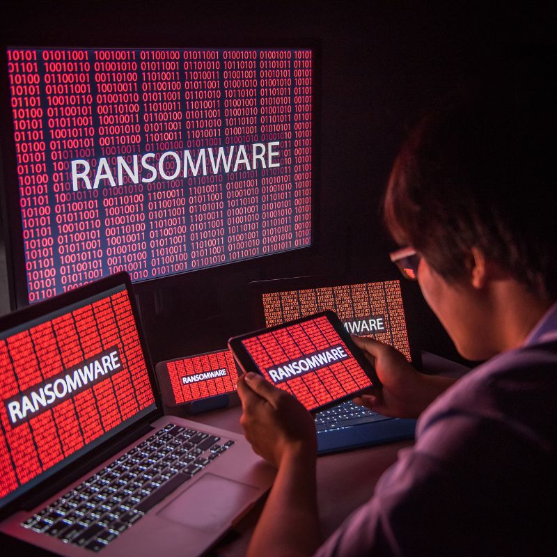 A person looks at a bunch of different screens that all say ransomware over red