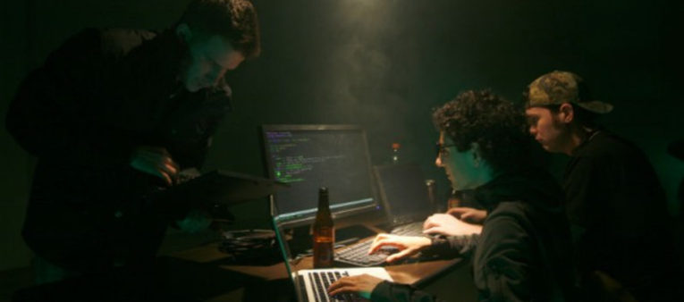 Men in a dark room on computers to imply hacking